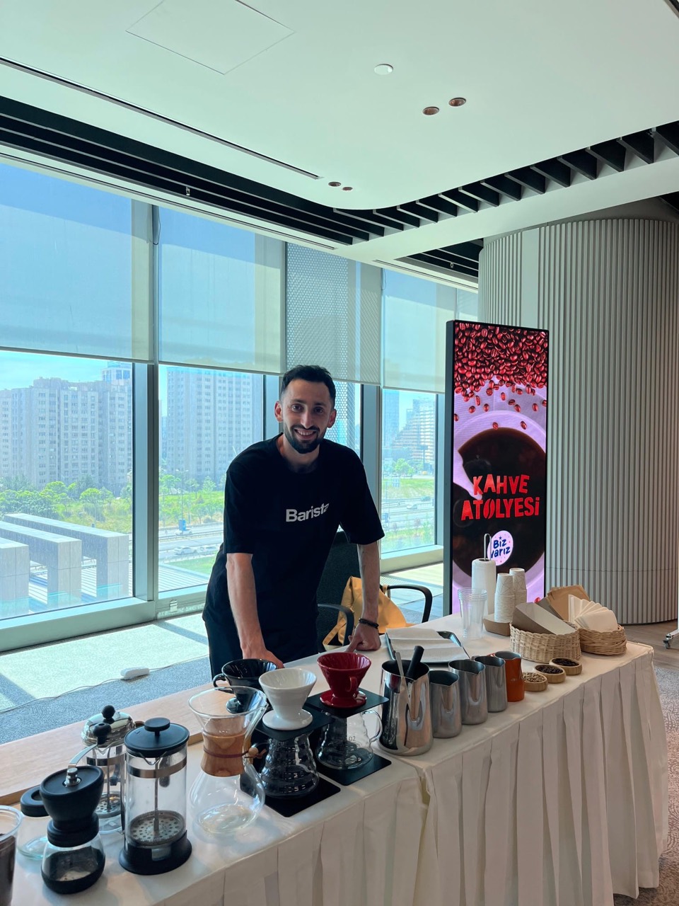 A person standing behind a table set with coffee brewing equipment